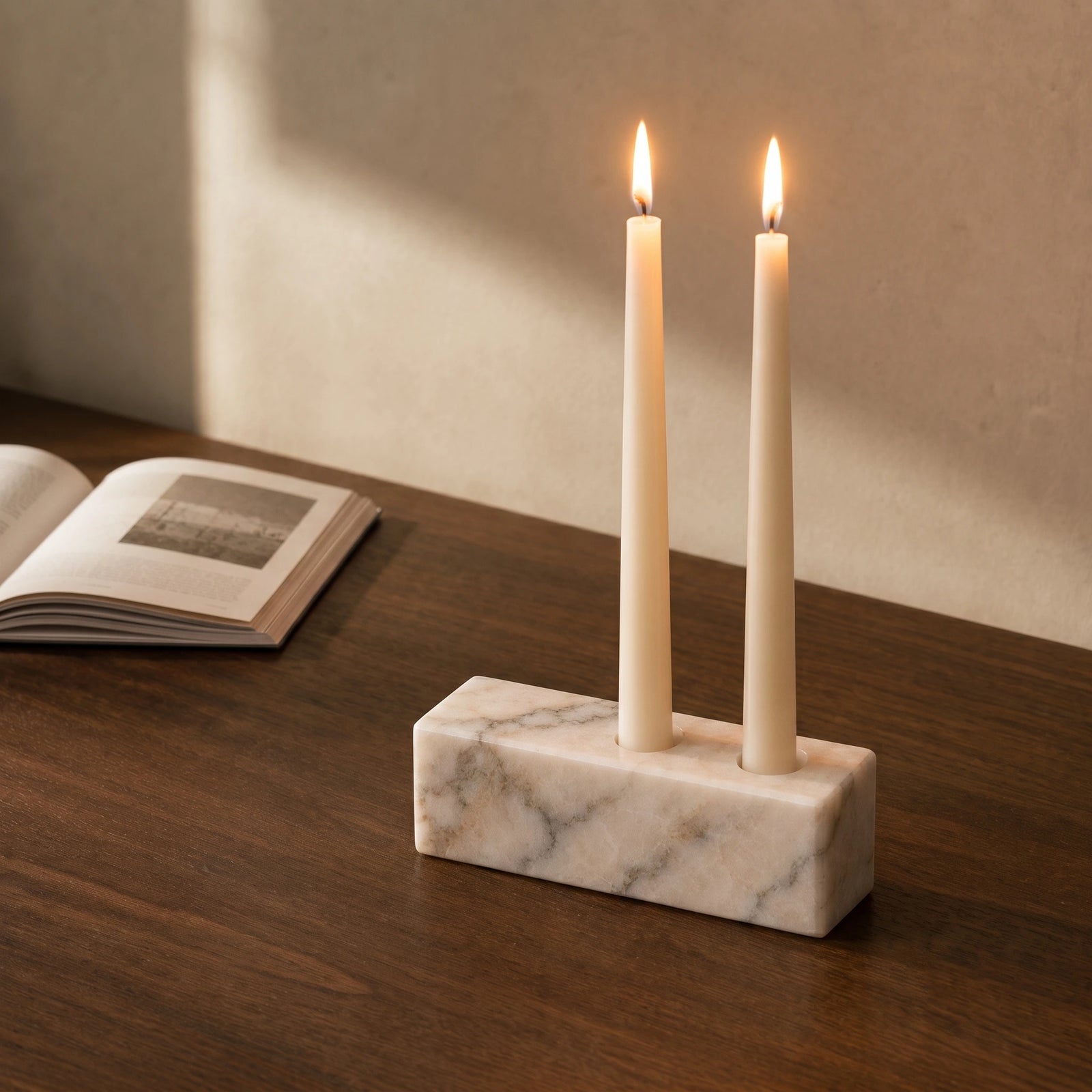 White marble candle holder styled on a walnut desk with an open book.
