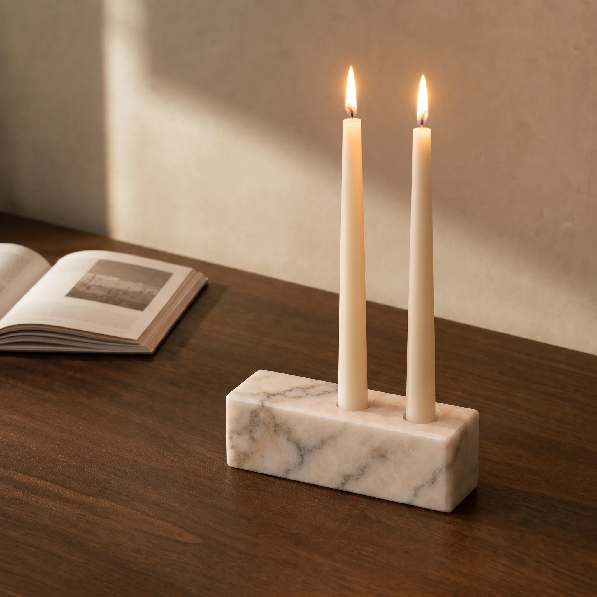 White marble candle holder styled on a walnut desk with an open book.