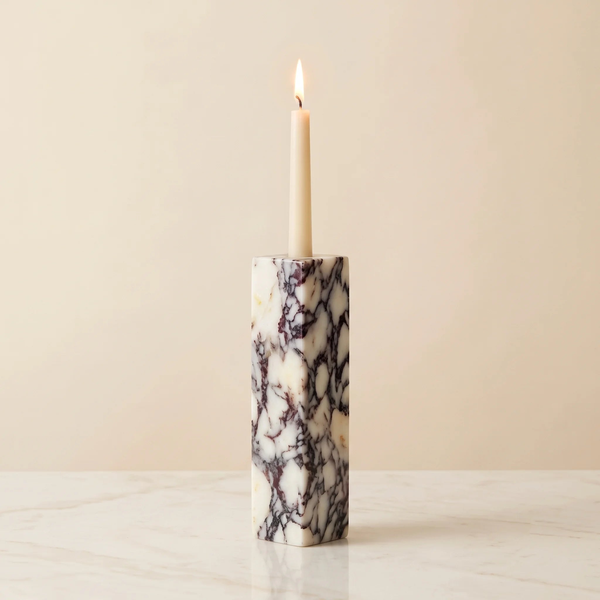 Monolith Candle Holder in Calacatta Viola — deep violet-veined marble with a lit taper candle