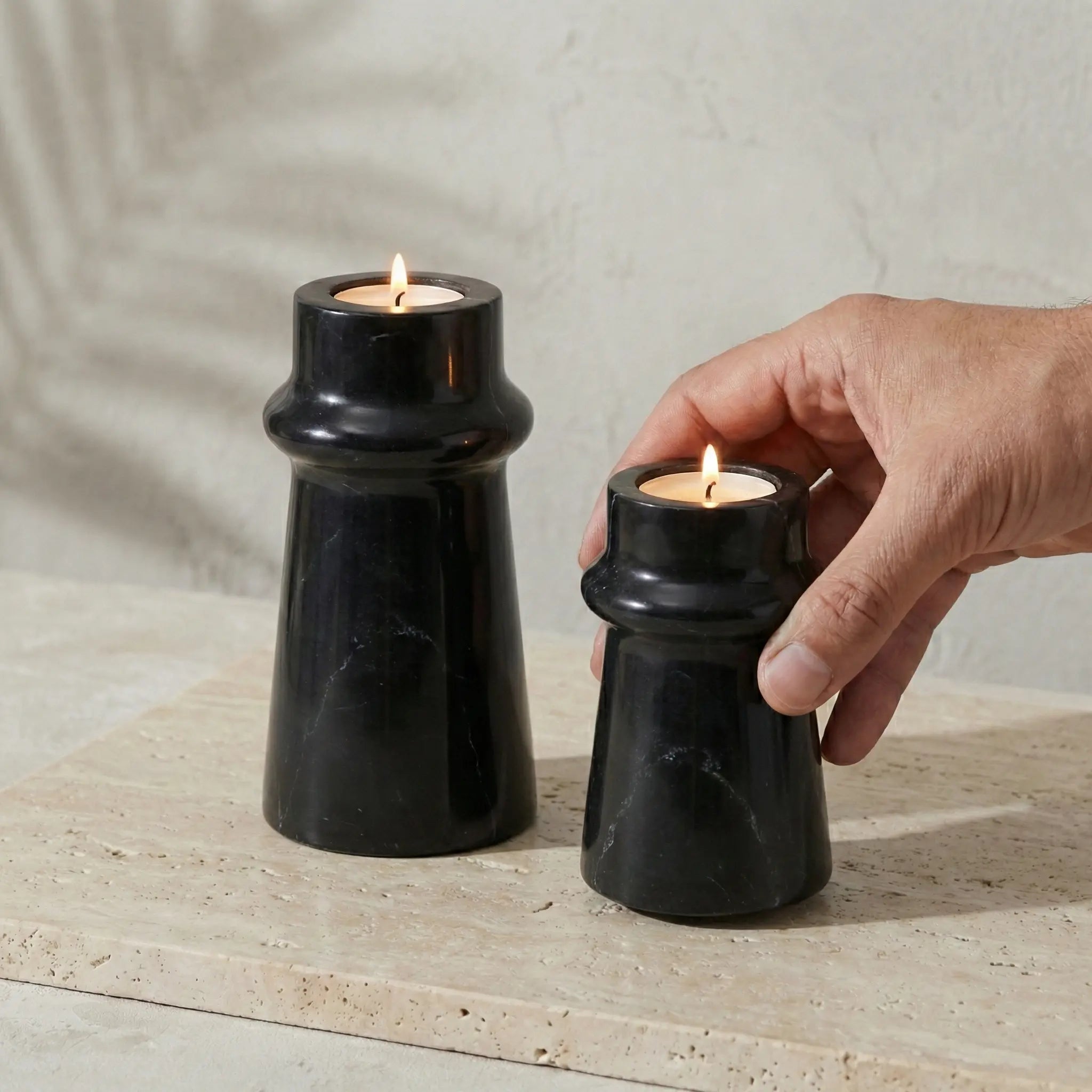 Hand lighting a candle in the Black Marble Taper Holder stone pedestal for ambient lighting