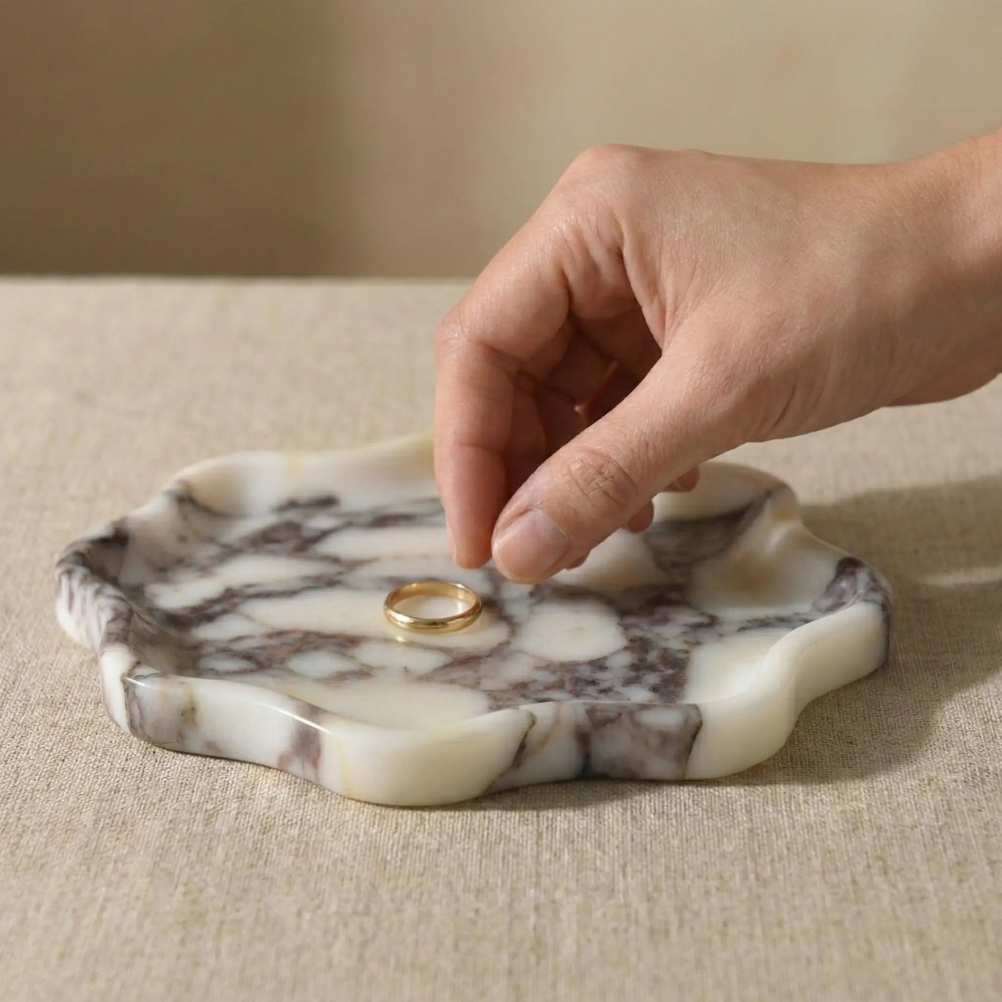 Calacatta Viola marble tray used as a luxury jewelry display for rings on a minimalist background
