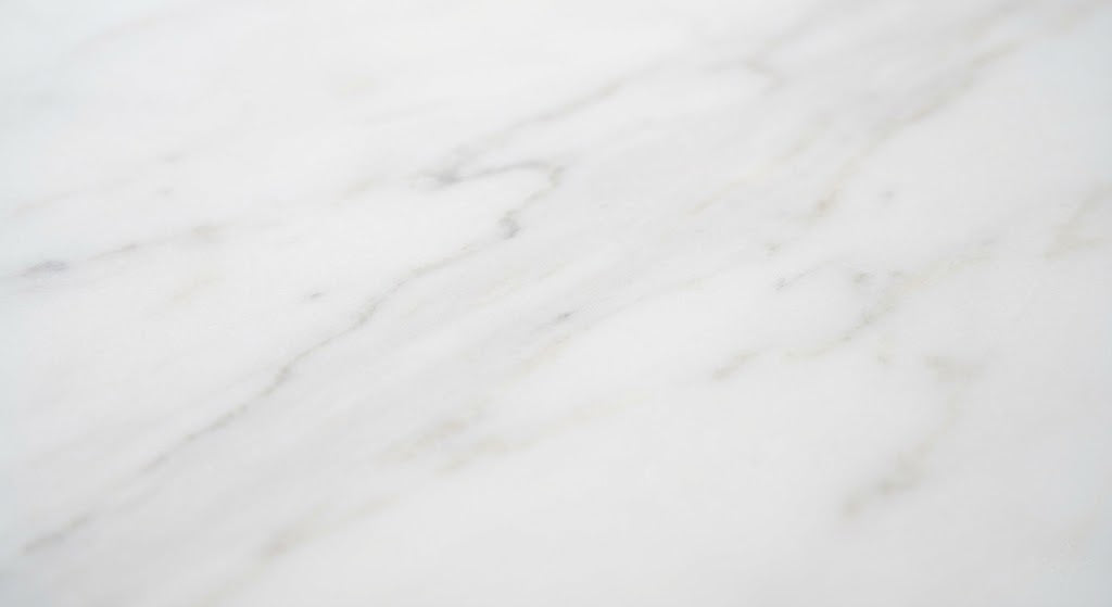 Elegant white marble stone texture featuring soft grey organic veining and a smooth polished finish.