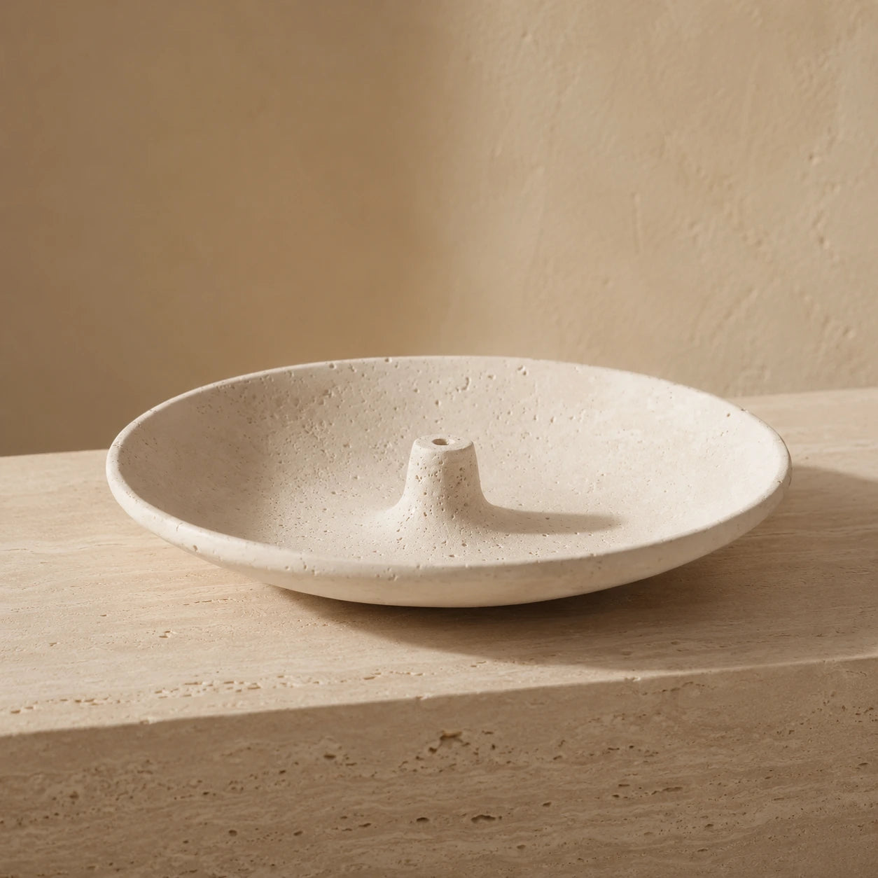 Ivory natural stone incense bowl with raised central incense holder and porous stone texture