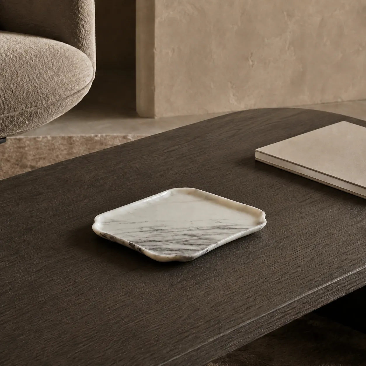 Natural marble tray on a smoked oak coffee table, showing its sculptural edge, grey veining, and compact 24 × 18 cm scale in a contemporary living room.