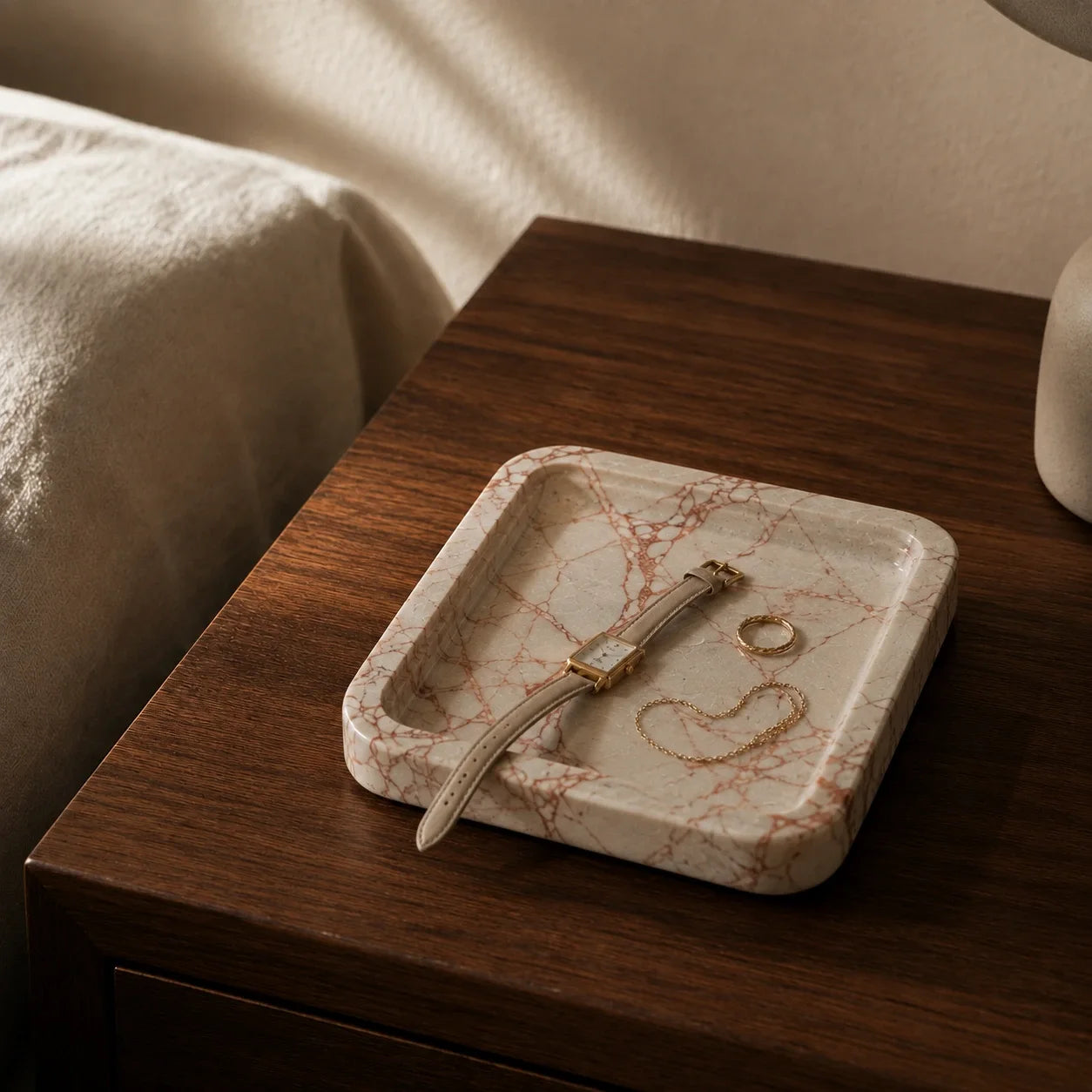 Small Calacatta Viola marble tray styled on a walnut bedside table with a watch, ring, and necklace, showing its use as a bedside catchall tray.