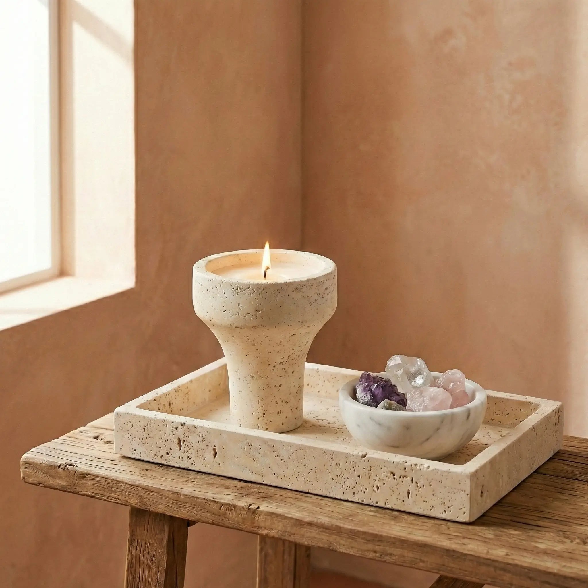 Travertine Chalice Holder with a burning candle on a matching stone tray with crystals.
