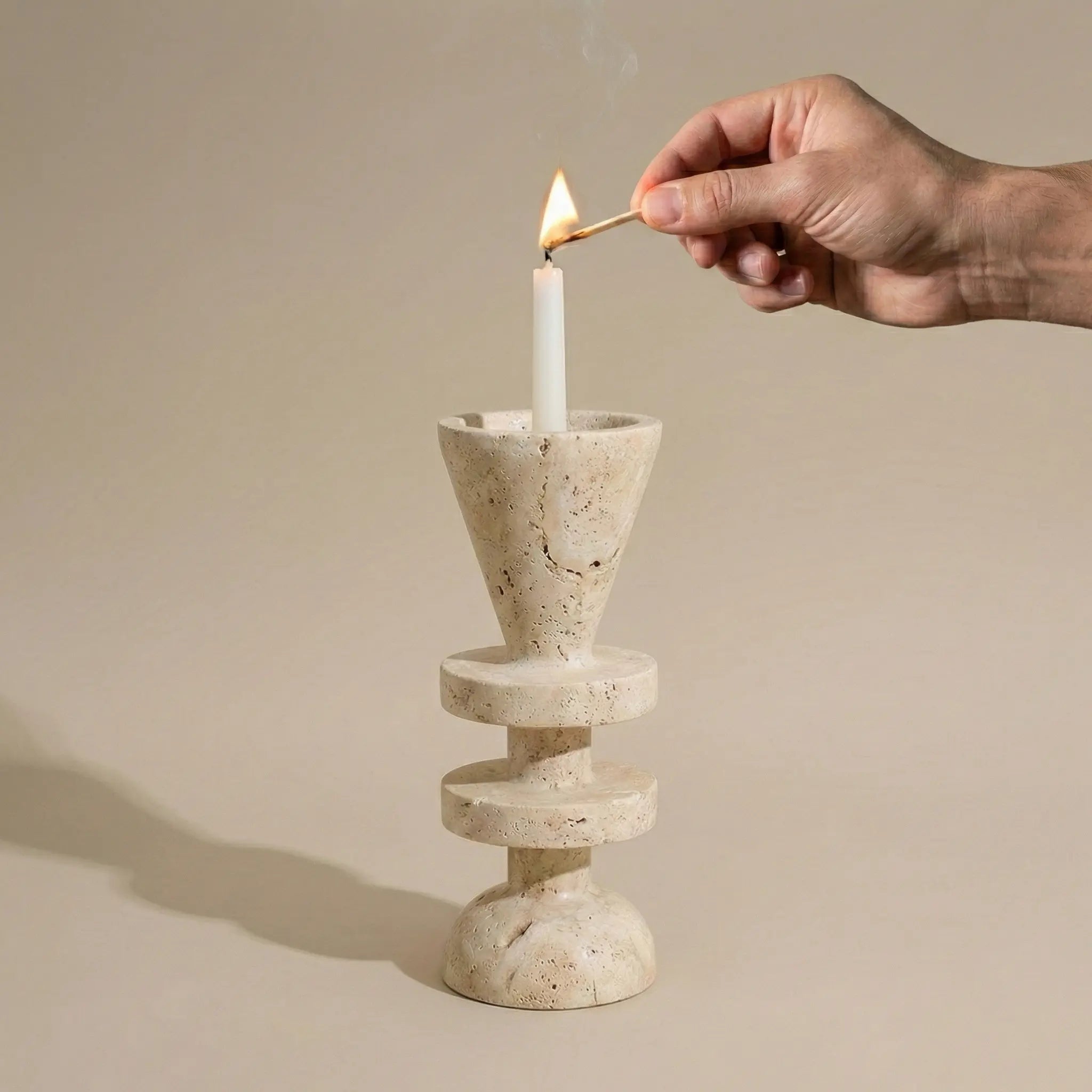 Person lighting a candle in the Travertine Tower Holder stone candle pedestal for ambient lighting