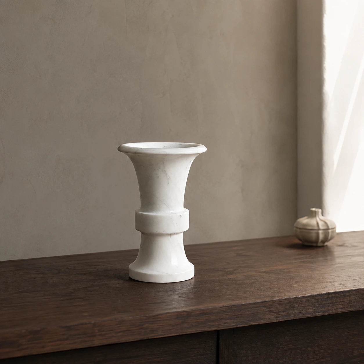 White marble flared candle holder on dark wood sideboard in natural light interior