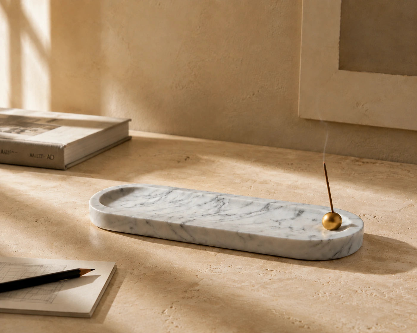 White marble incense tray with brass sphere holder styled in a warm minimalist designer workspace