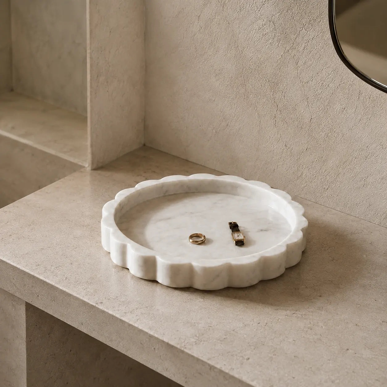 White scalloped marble tray on a pale limestone surface with a watch and ring, showing its sculptural edge, natural stone texture, and compact scale.