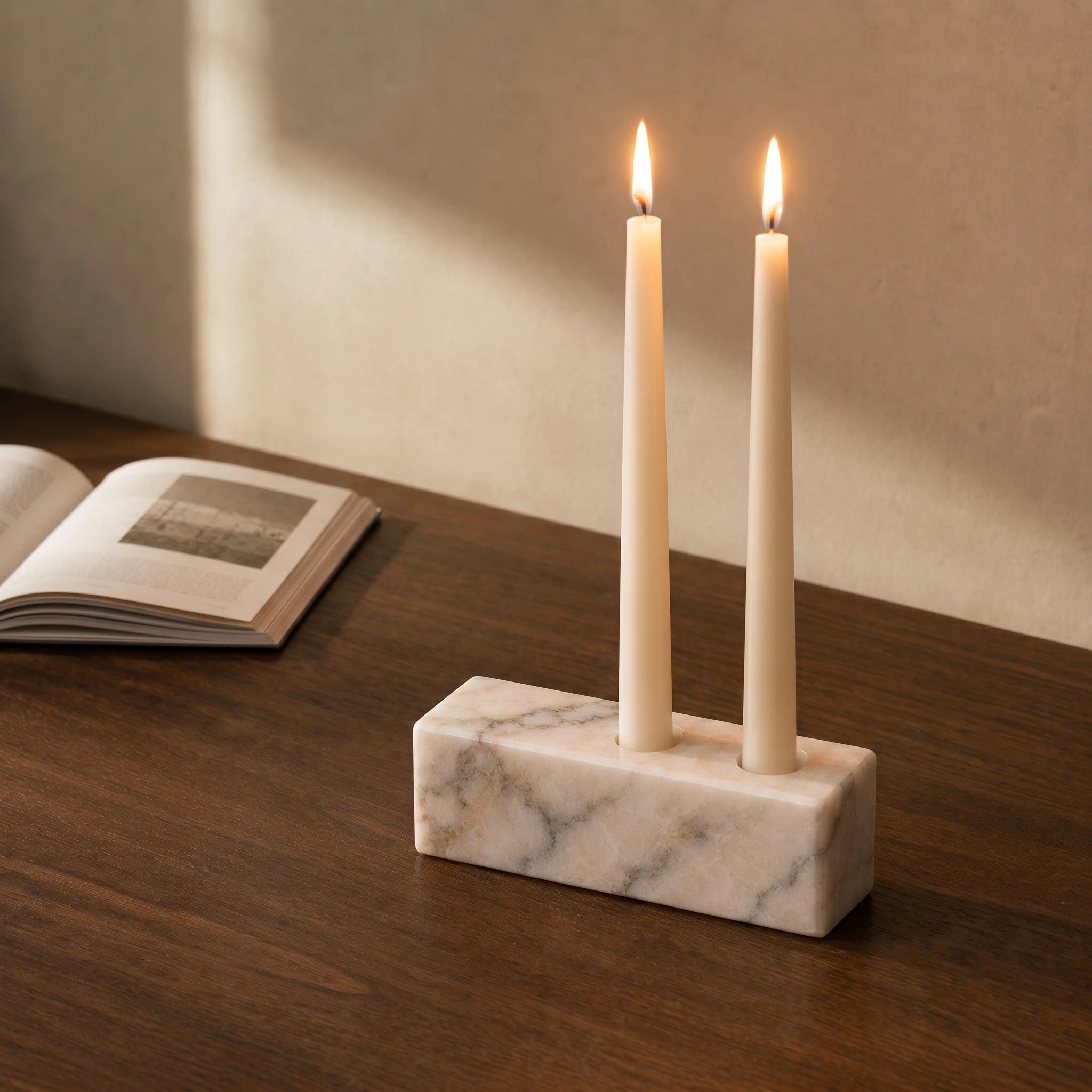White marble candle holder styled on a walnut desk with an open book.