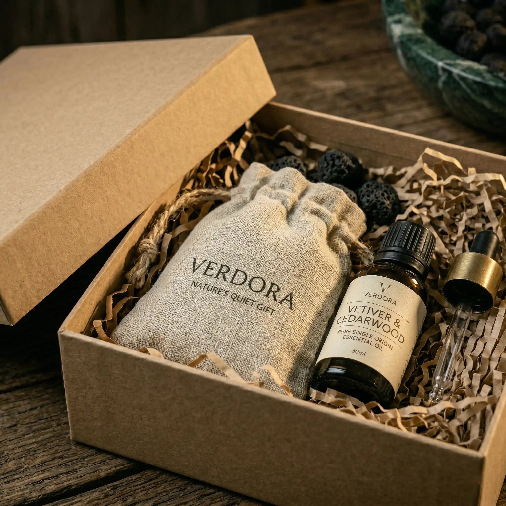 Elegant gift packaging for lava stone diffuser set including a green marble bowl, essential oil, and a branded linen bag in a kraft box.