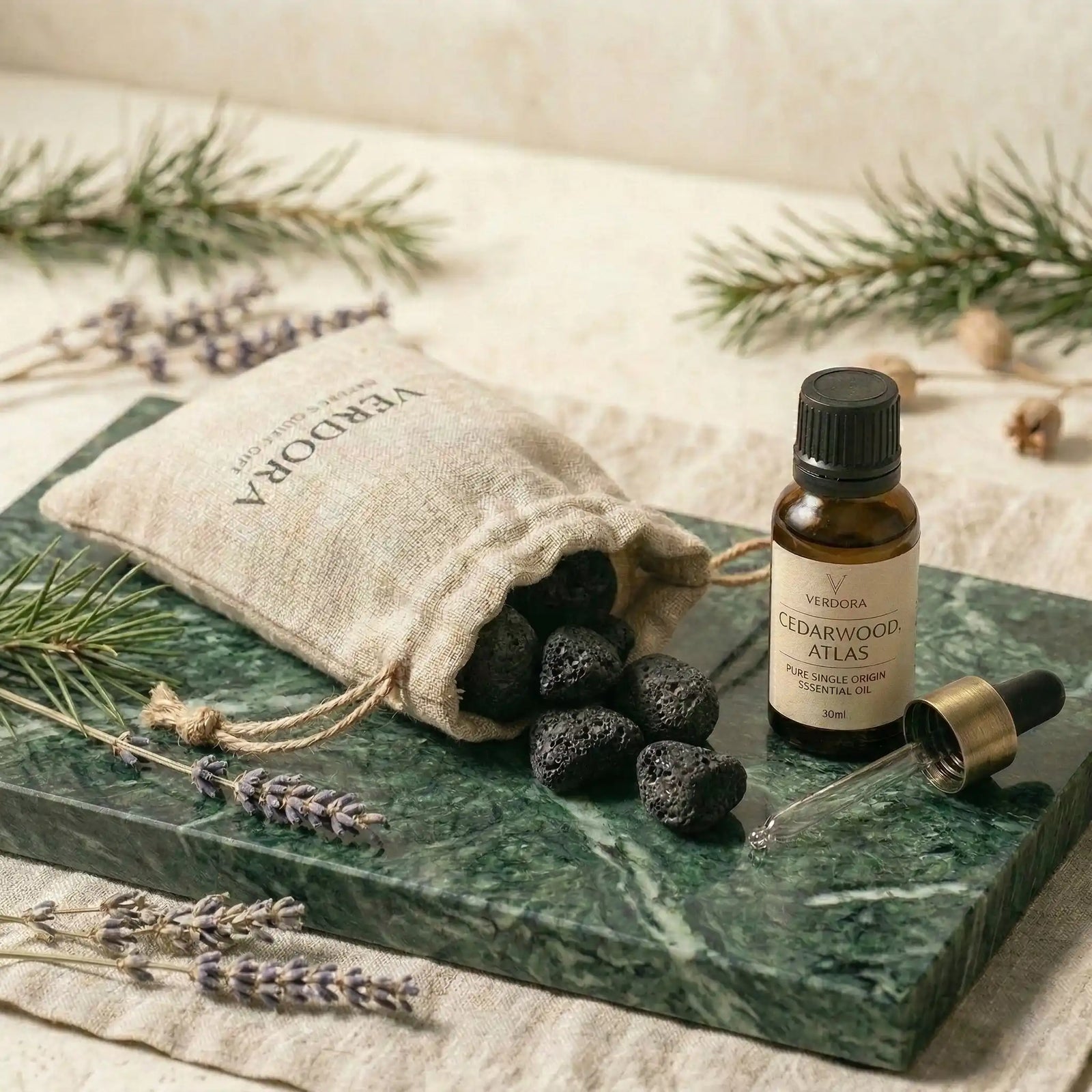 Luxury green marble diffuser tray set with natural lava stones, an essential oil bottle, and a linen pouch on a stone surface.