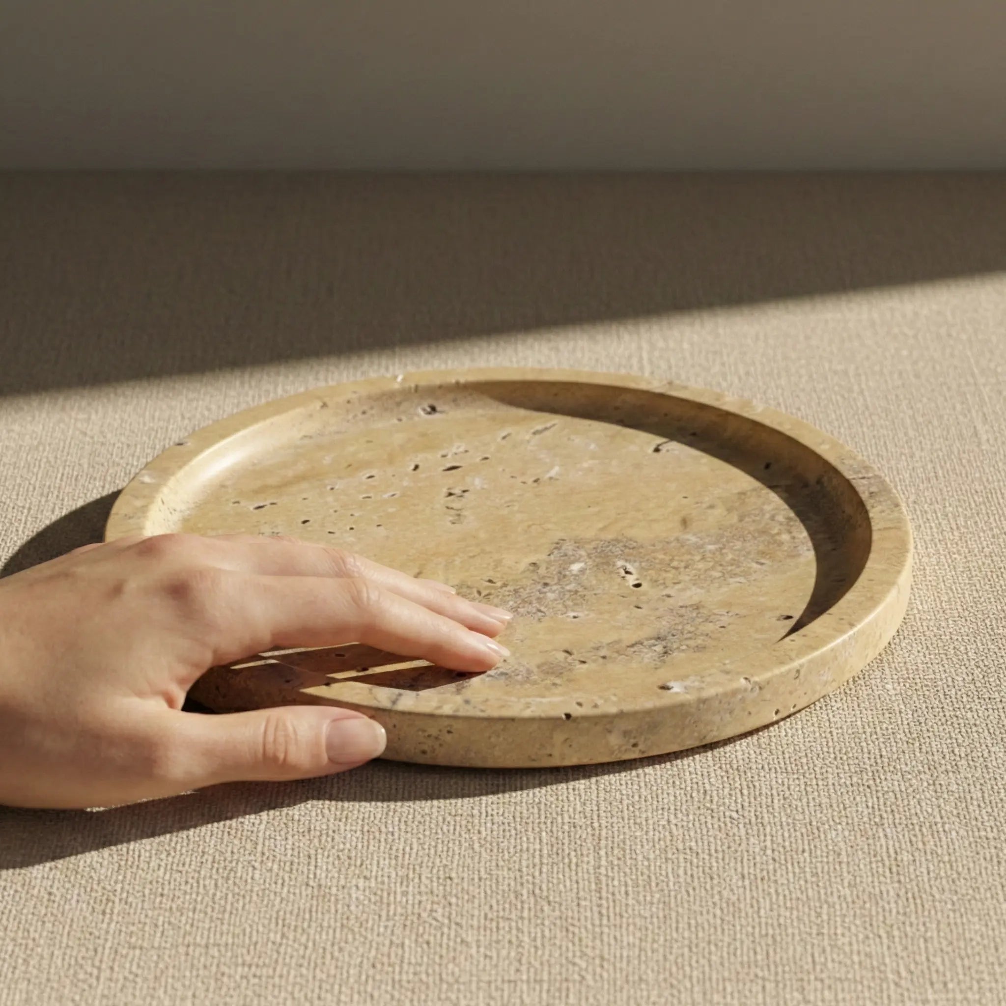 Hand touching the surface of Amber Marble Round Tray to show natural honey stone texture