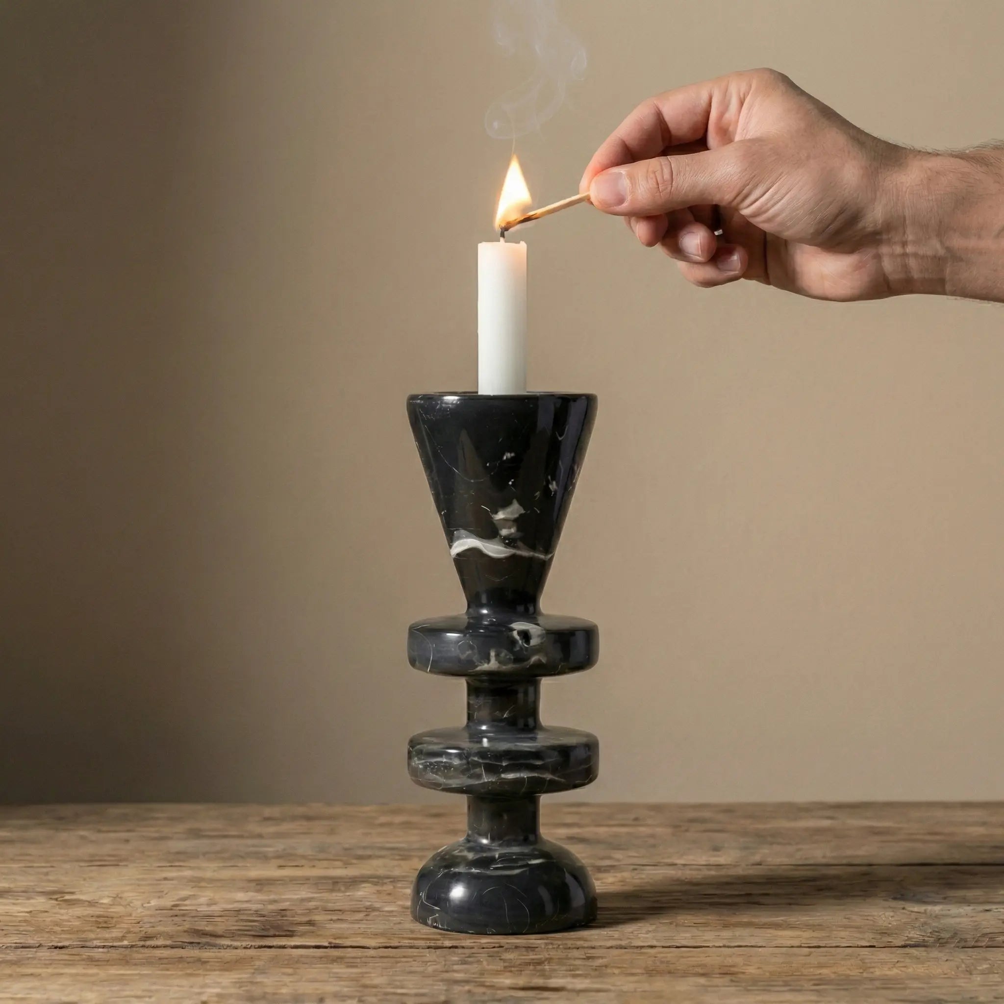 Hand lighting a candle in the Black Marble Tower Holder stone pedestal for ambient lighting