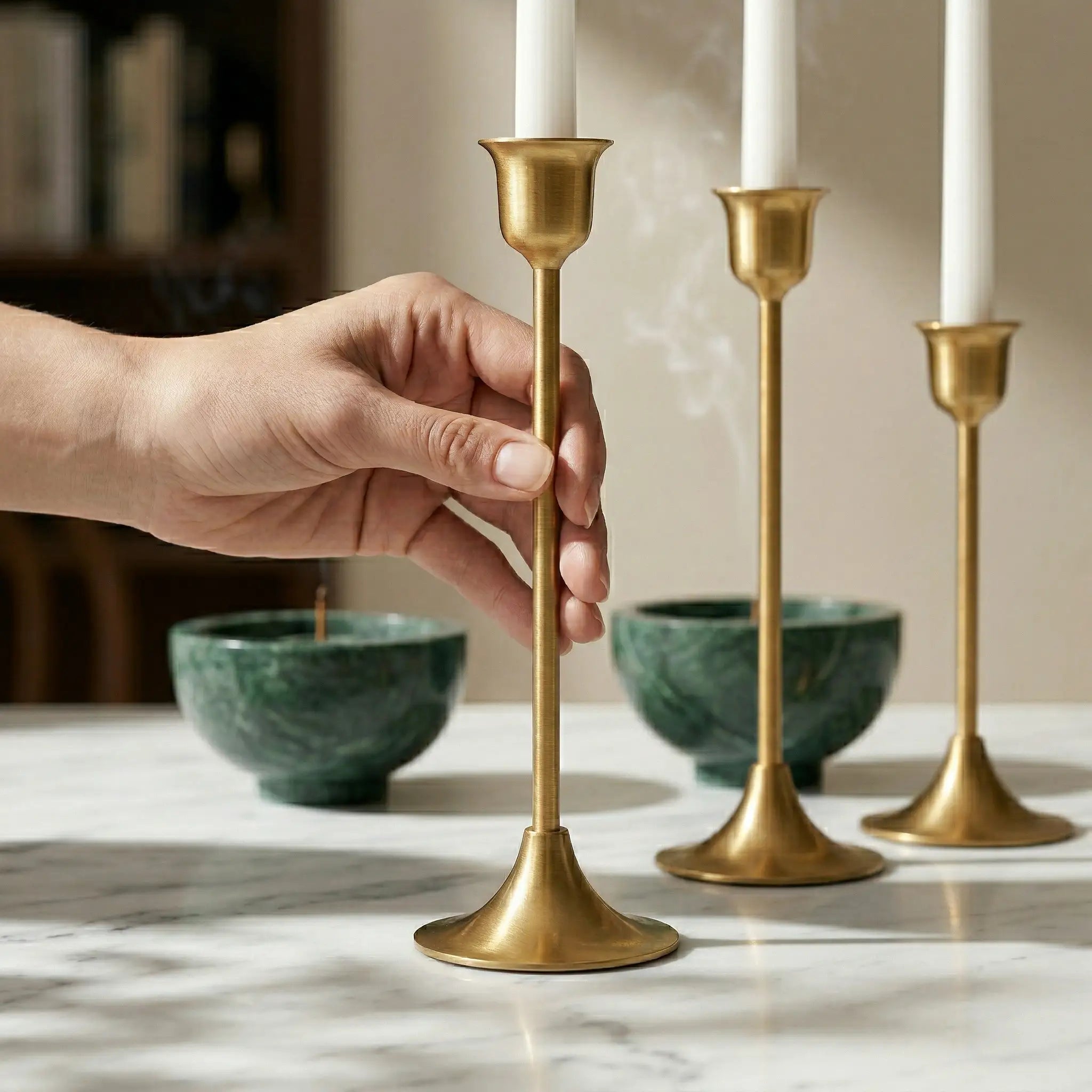 Brass Monolith Trio candlestick holders styled alongside a green marble incense bowl on a stone surface.