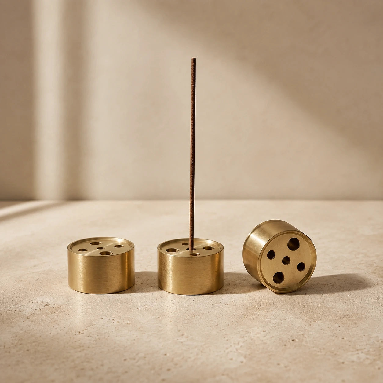 Brass cylindrical incense stick holder with five-hole insert – set of three on travertine surface