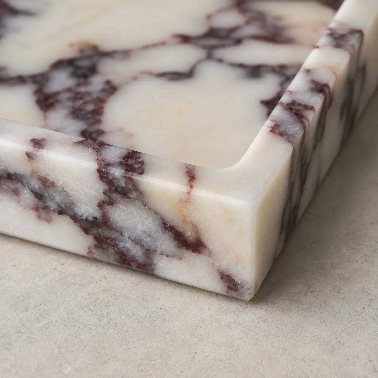 Close-up detail of Calacatta Viola marble tray showing natural purple veining, polished edges, and unique stone texture.