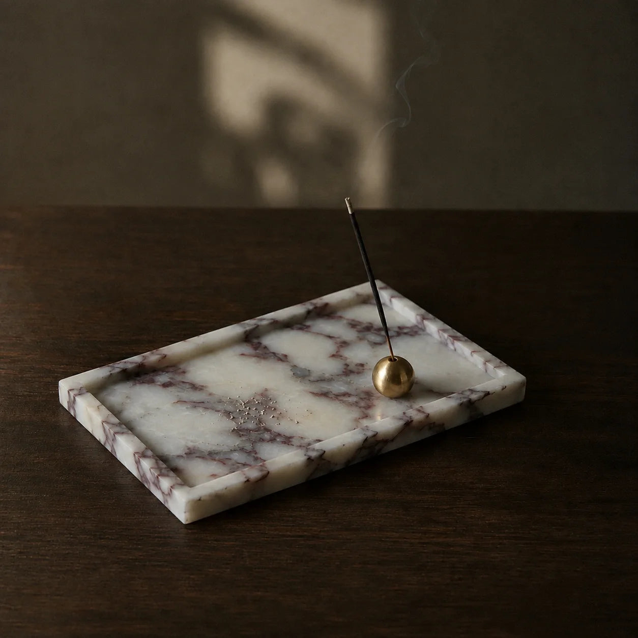 Calacatta Viola marble tray with brass incense holder styled as a minimalist incense ritual object on a wooden table.