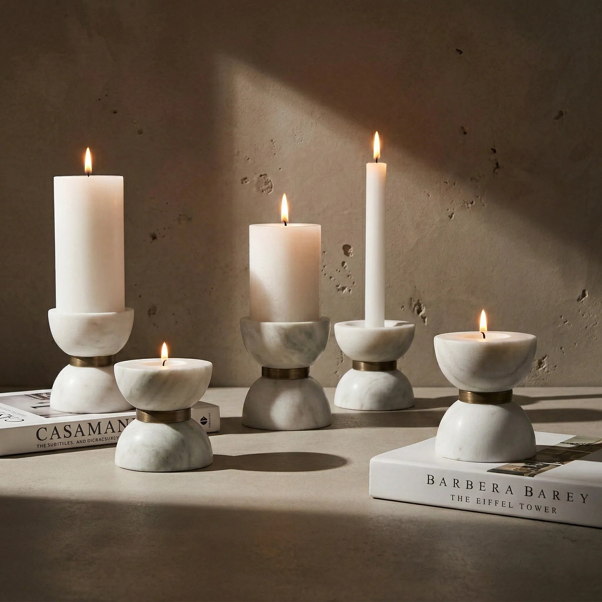 Close-up of various Funnel Monolith Pillar stone holders with burning candles in a cozy setting