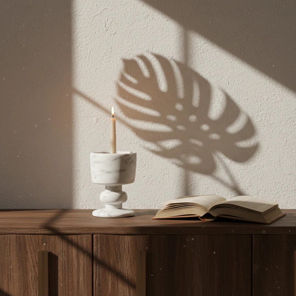 Marble Goblet Holder white stone candle pedestal on a wooden desk with a book and leaf shadows