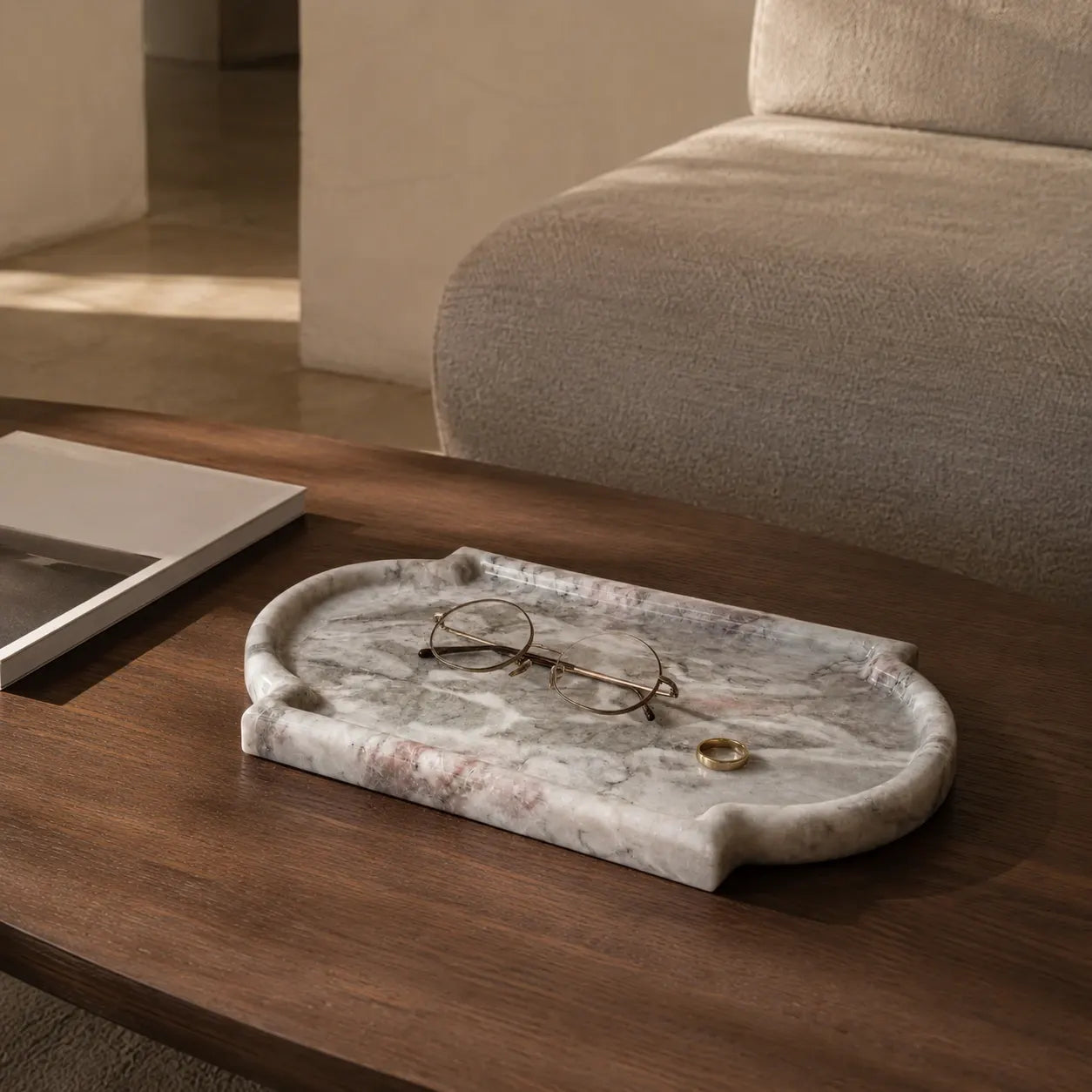 Calacatta Viola marble tray with glasses and gold ring on dark wood coffee table in living room