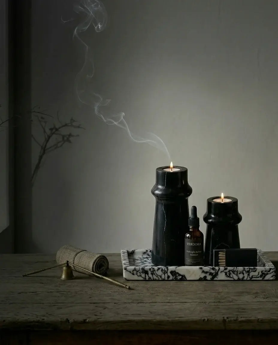 Moody interior styling featuring a set of black marble pillar candle holders and incense bowls on a dark textured surface.