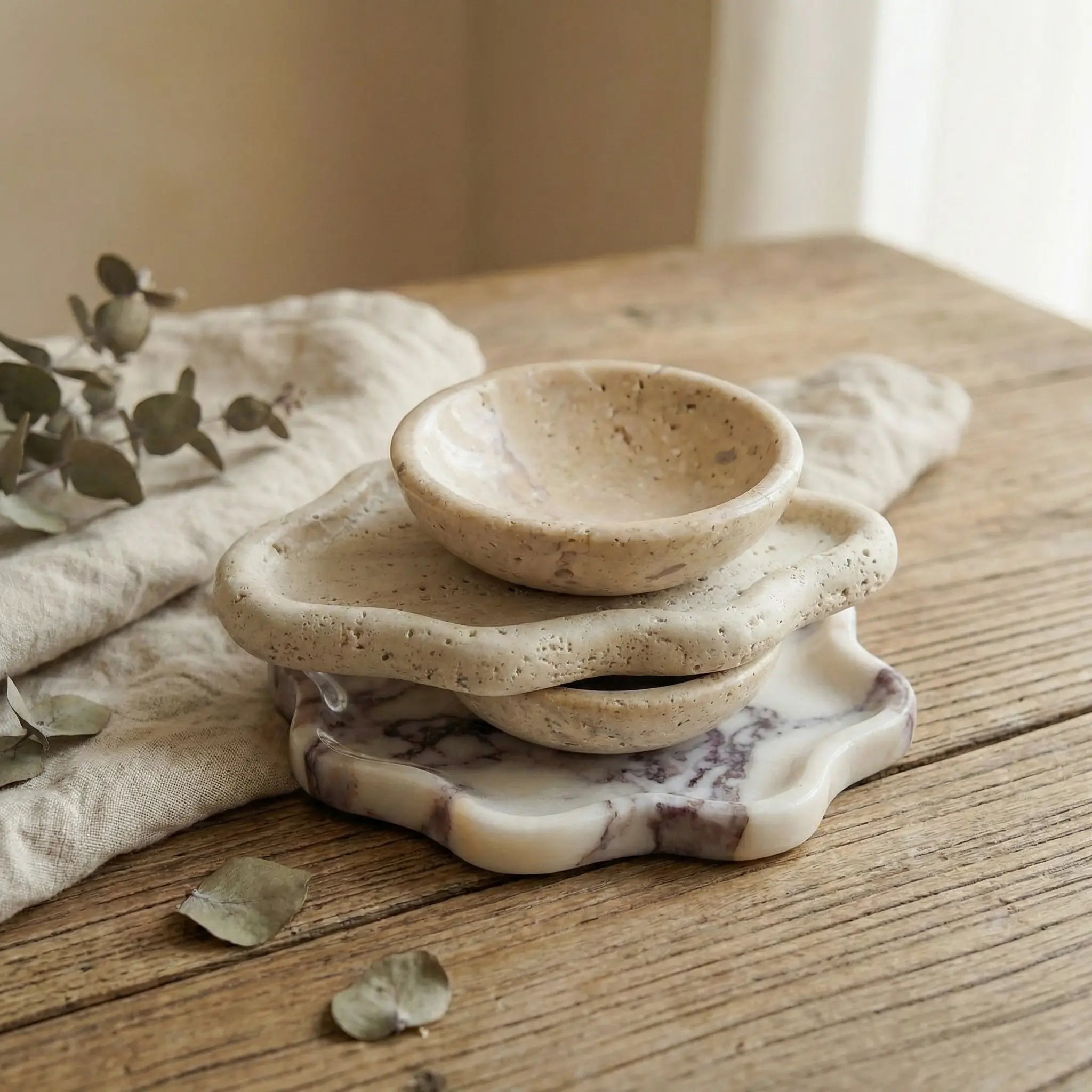 Stack of Travertine and Calacatta Viola marble cloud trays showing natural stone texture contrast