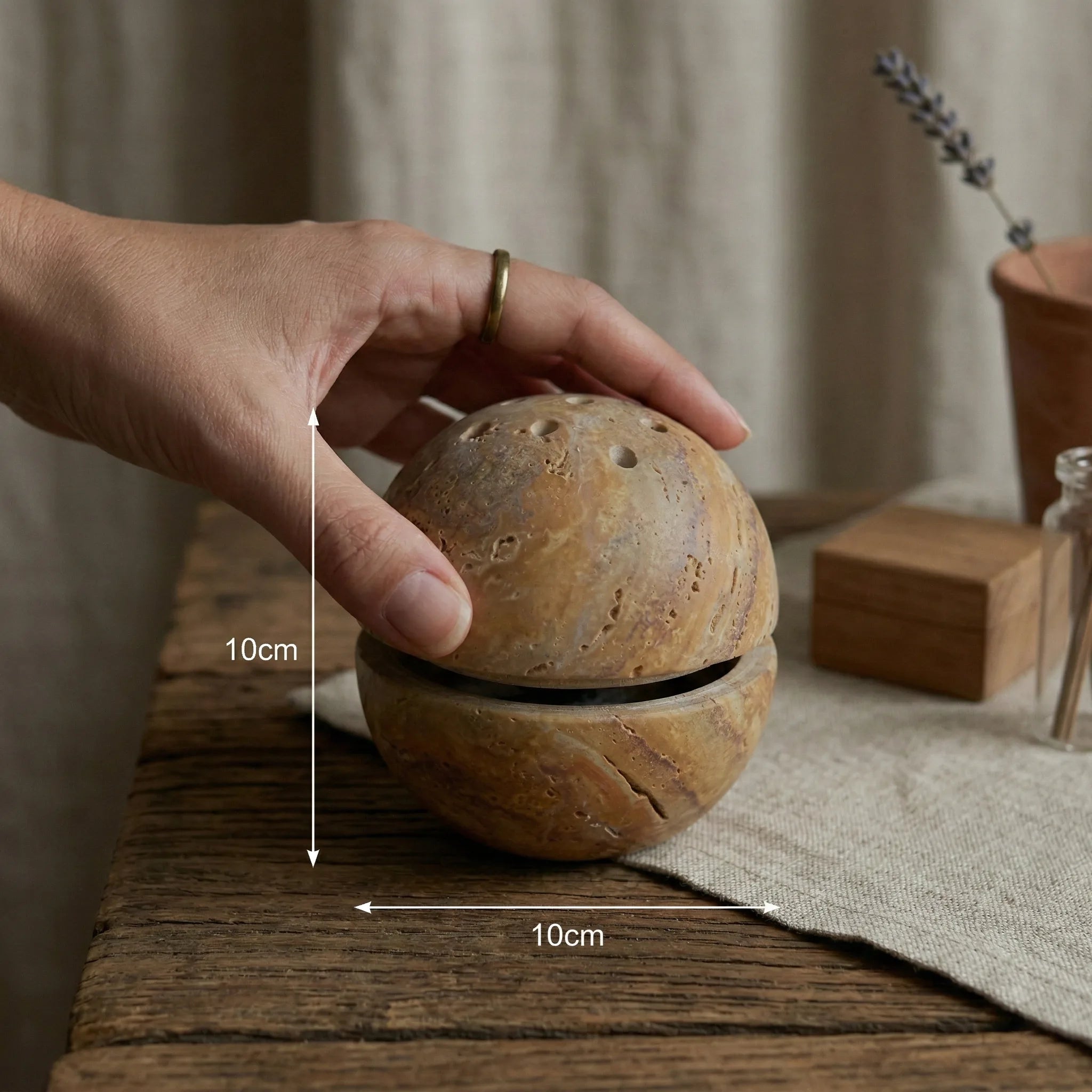 Hand holding Travertine Core Vessel stone incense holder for size and scale reference