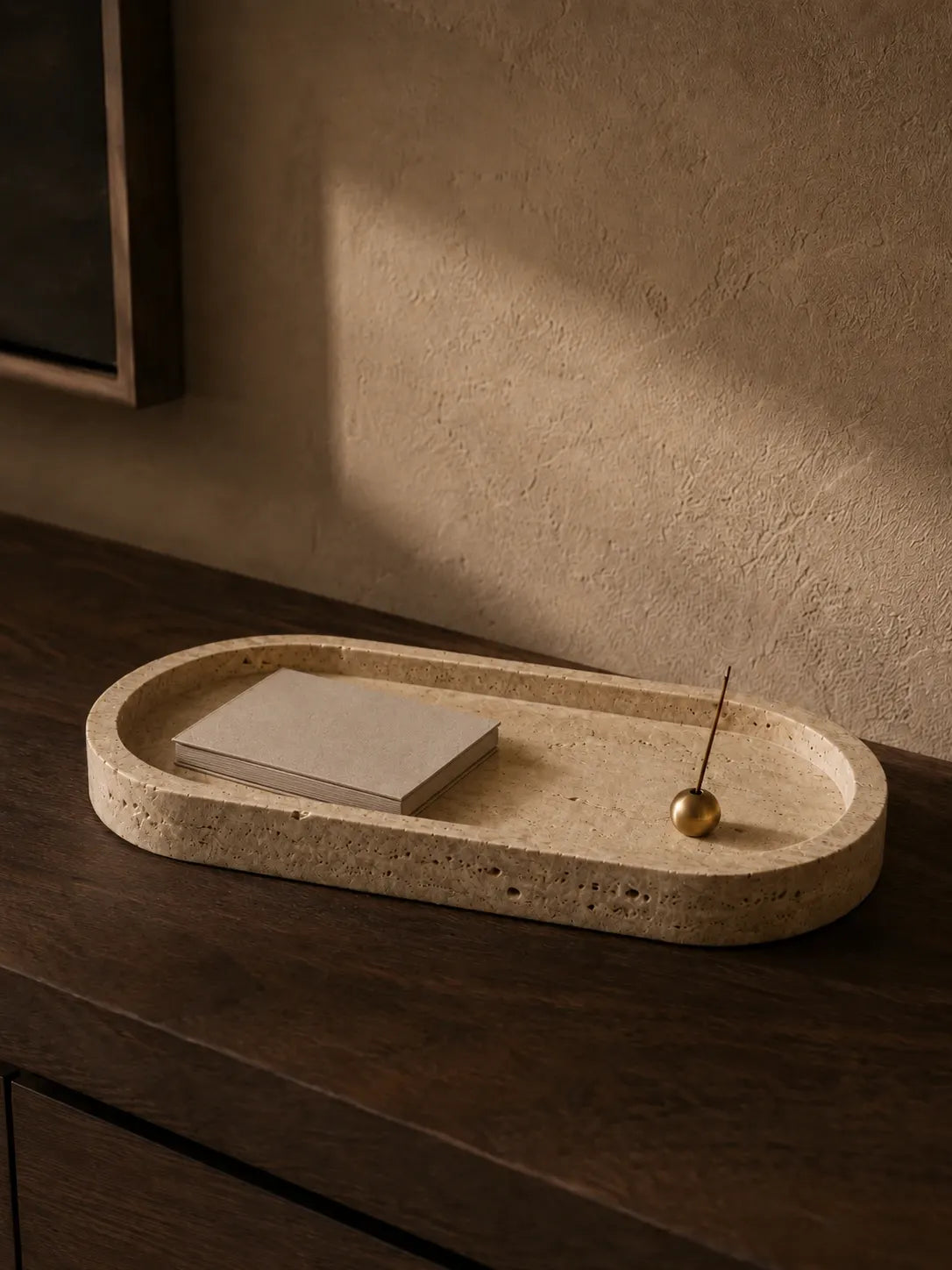Natural travertine long tray with a small brass incense holder in a warm evening interior, revealing the stone surface texture, low profile design, and timeless material character.