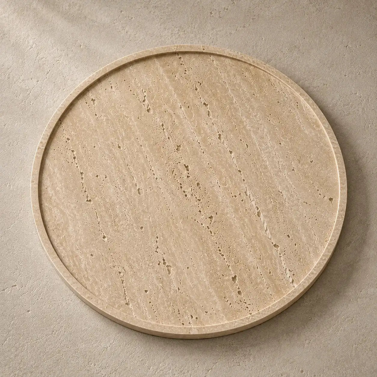 Close-up of a round travertine tray showing natural pores, linear veining and a hand-polished stone surface.