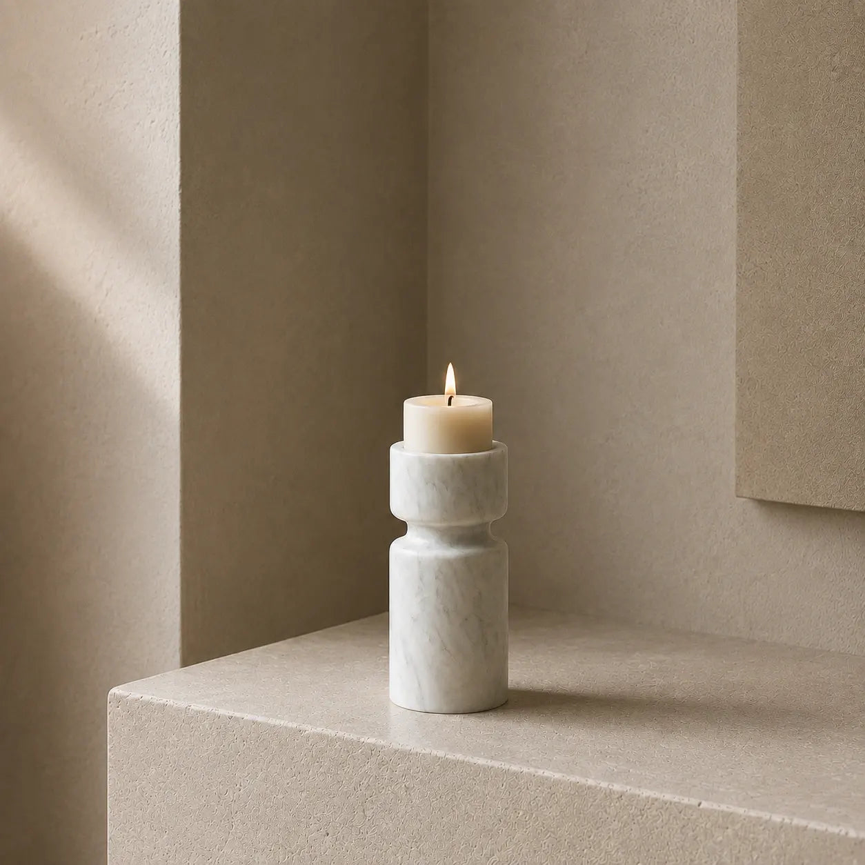 White marble candle holder with an ivory candle in a warm architectural interior.