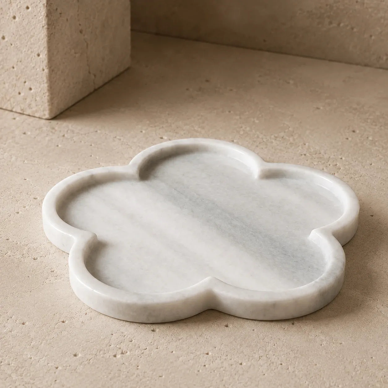 White natural marble cloud-shaped tray with a soft organic silhouette on a limestone surface, showcasing its rounded edges, shallow carved design, polished stone finish, and subtle natural variation.