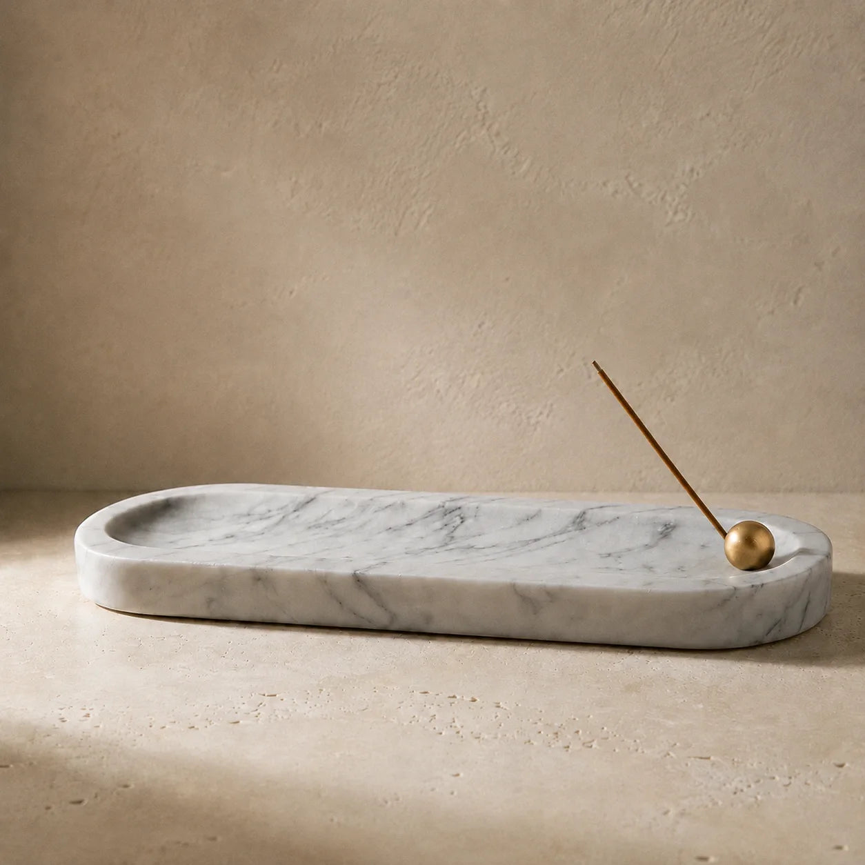 White marble incense tray with brass sphere incense holder and natural stone texture